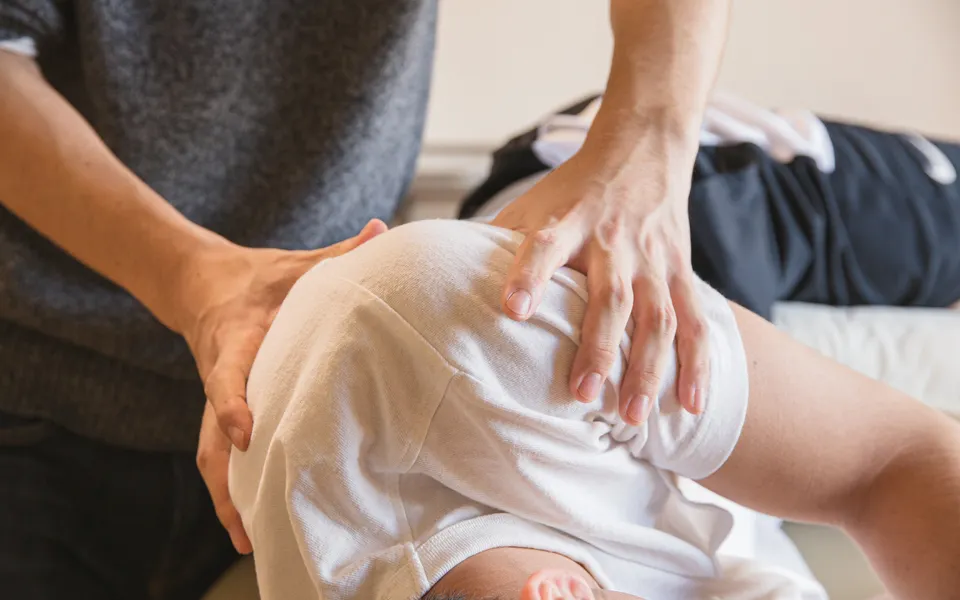 Physiotherapist working hands-on across a patient's back and shoulders