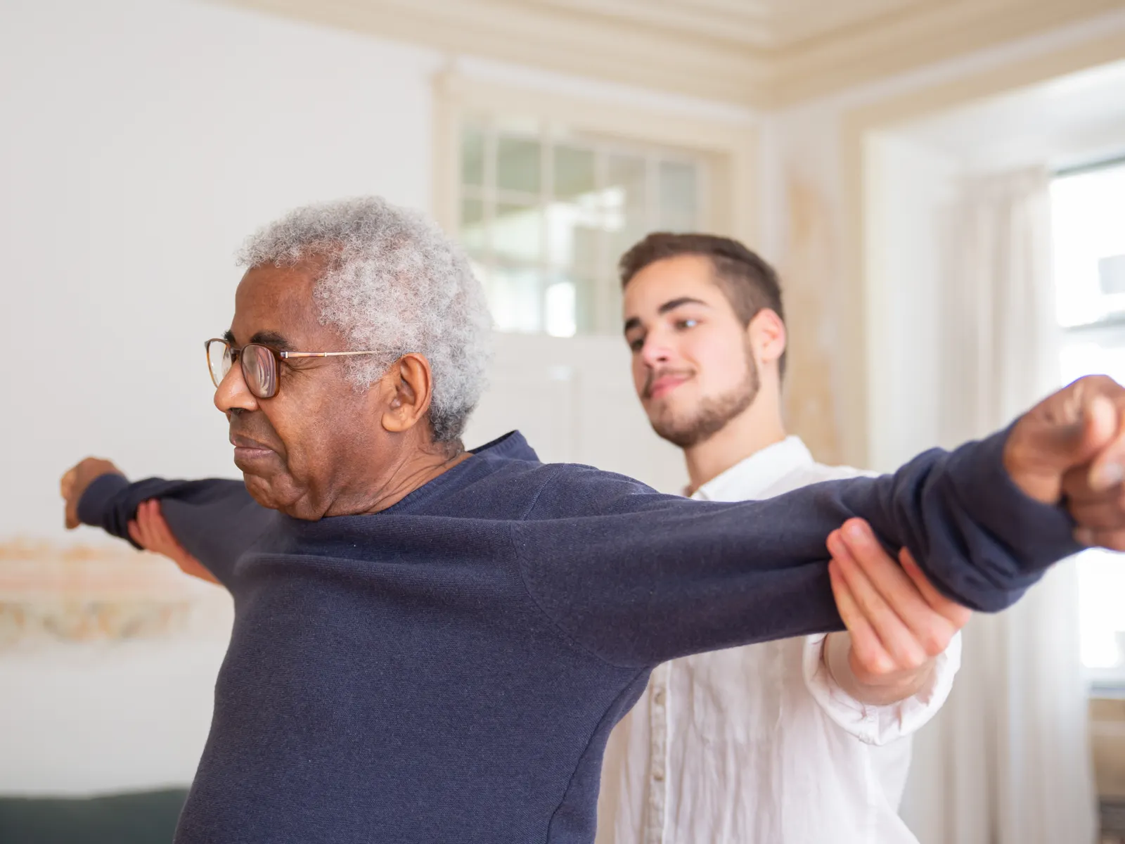 Physiotherapist assisting an older patient with guided stretching exercises