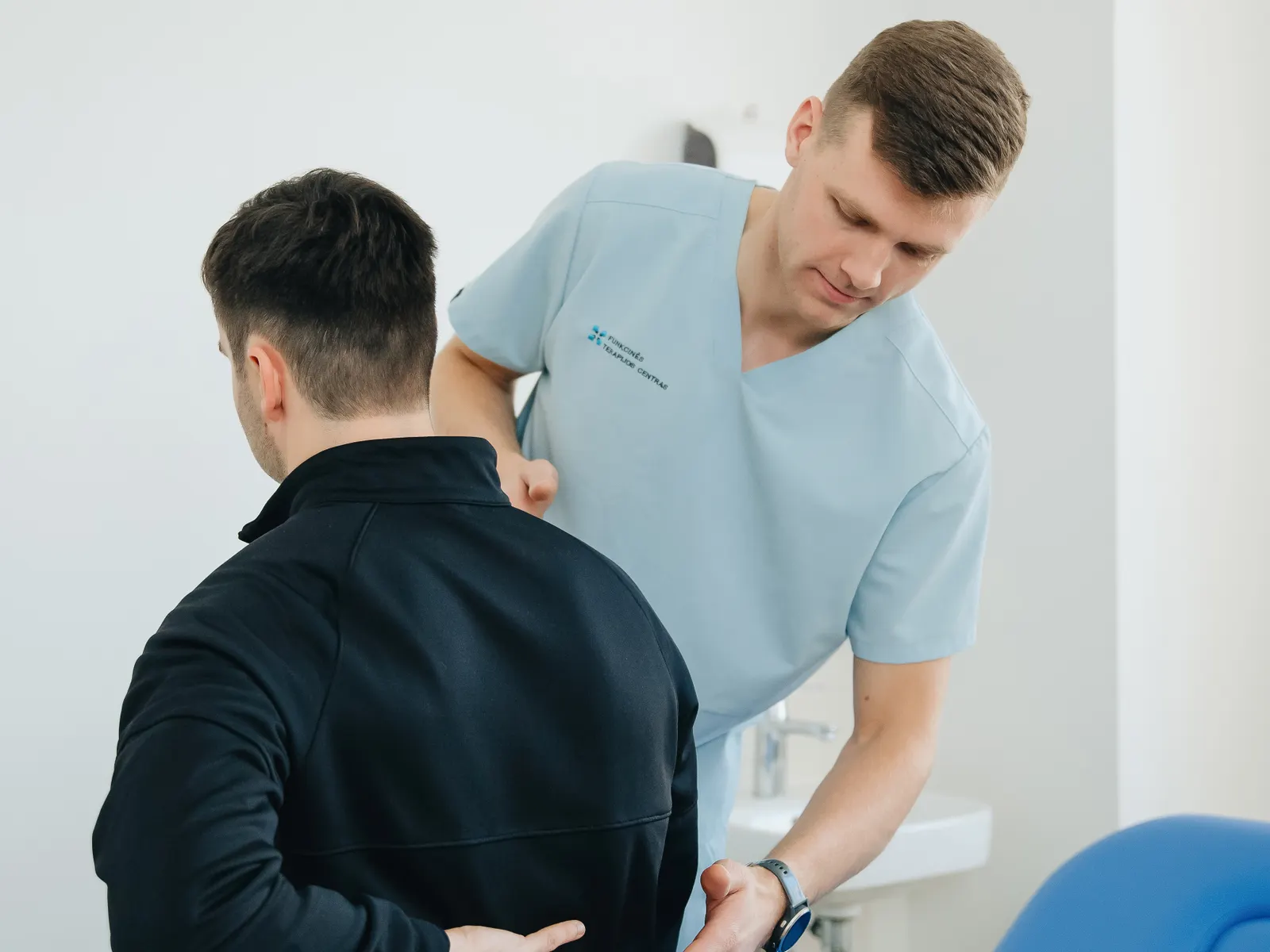 Physiotherapist assessing a patient's back during a one-on-one clinic session